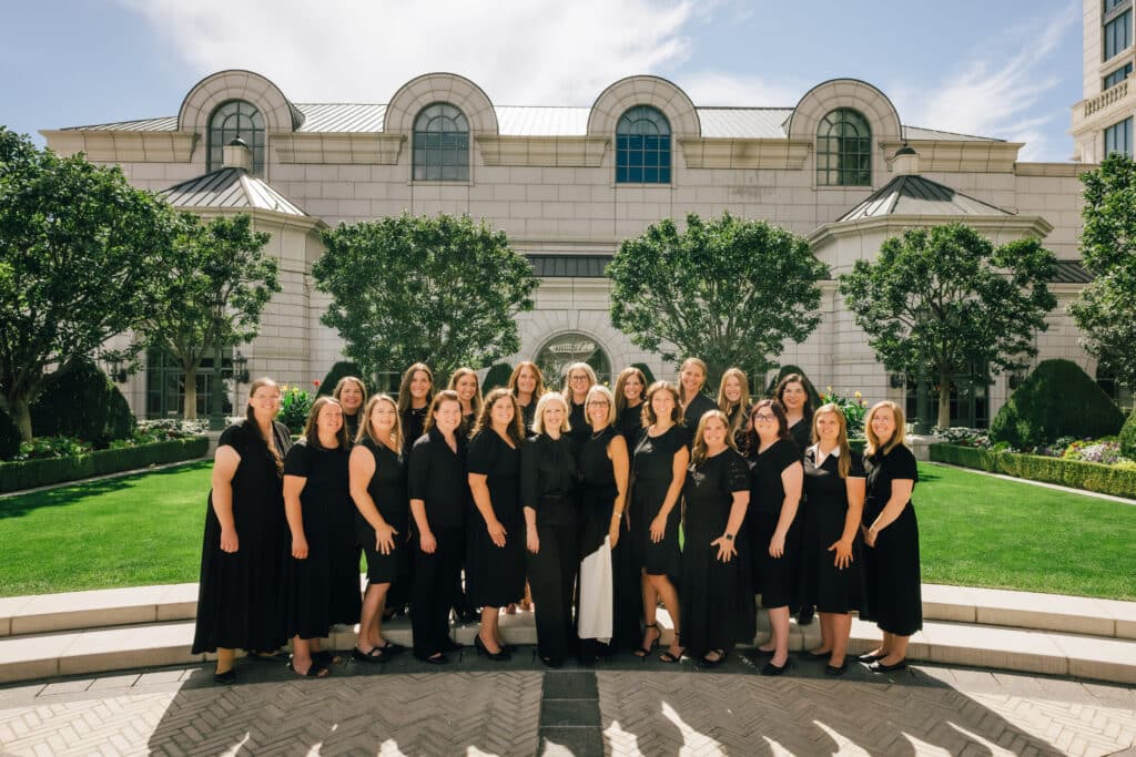 Group of team members, dressed in professional, black dress, standing outside